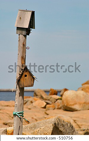 Bird house on a pole near the rocks on the ocean