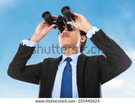 young business man looking through binocular under the blue sky