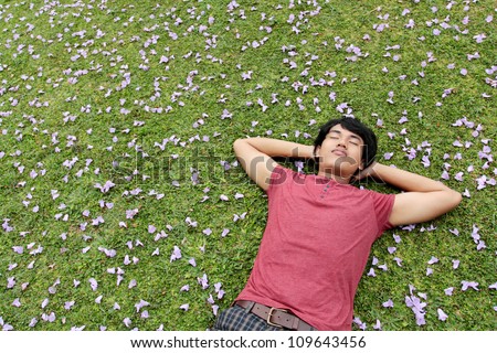 happy asian man lying on the grass relaxing