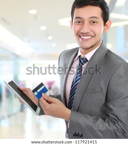portrait of young business man hold a tab and credit card