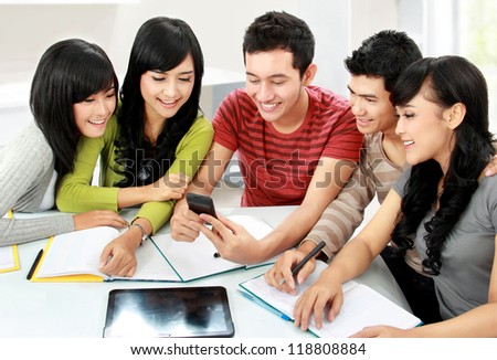 Group of asian students looking at handphone together