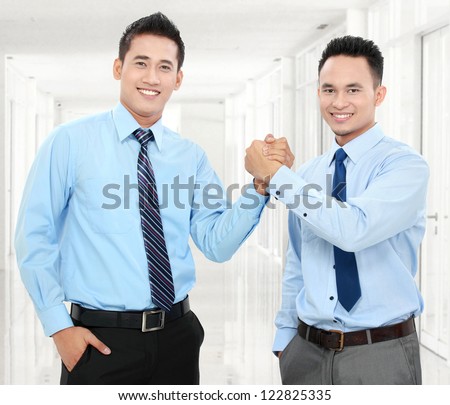 Portrait of two happy business men shaking hands with each other in office