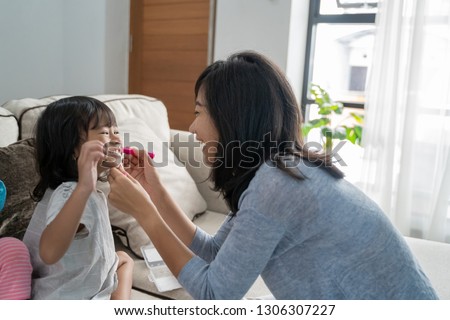asian mother face painting her little daughter at home. making some cute animal faces