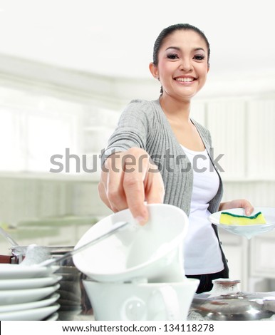 smiling woman happily washing dishes in the kitchen