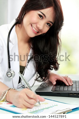 smiling asian female doctor working in office