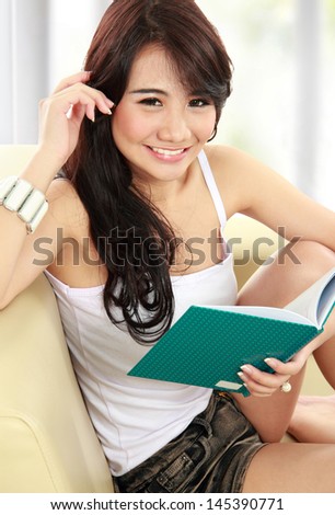 smart young teenager sitting on sofa and read a book