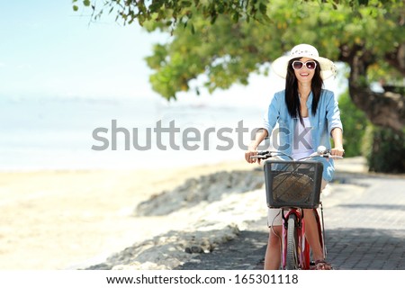 carefree woman having fun and smiling riding bicycle at the beach