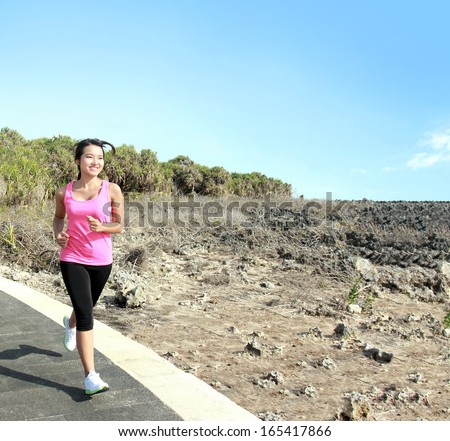 Beautiful fitness model in pink running on jogging track