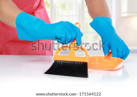 close up portrait of hand with glove using cleaning broom to clean up the table
