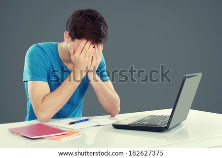 Tired of studying. young man covering his head while sitting. gesture of depression