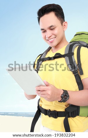 portrait of a smiling man backpacker using tablet pc using tablet computer
