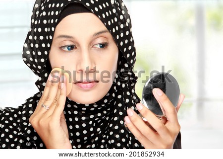 beautiful young adult woman with cotton pad. applying face powder