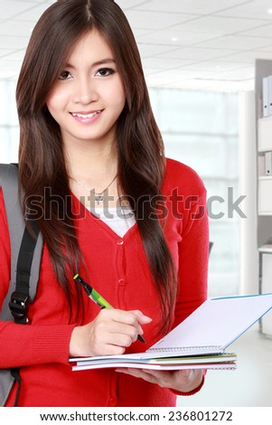 Beautiful female student holding books and smile to the camera isolated on white background