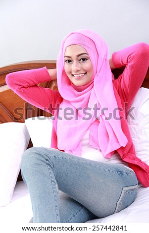 portrait of young muslim woman relaxing body with hand behind neck on bed