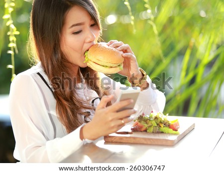 portrait of multitasking woman having lunch while texting on her mobilephone