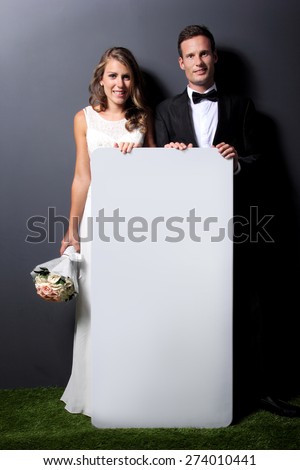 full length portrait of  young newlywed couple holding white board