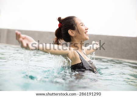 A portrait of a Happy beautiful asian woman enjoying time on the pool, with open arms and closed eyes