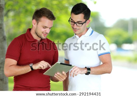 portrait of two college students looking an information using tablet at college park