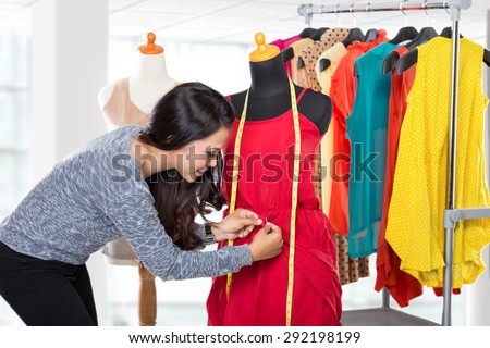 A portrait of a young fashion designer or Tailor working on a design or draft, she make a little adjustment to her work