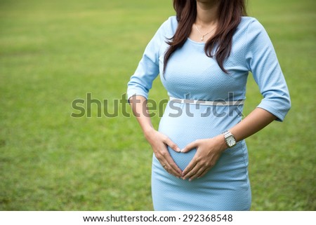 A portrait of asian pregnant woman with hart shape hands gesture on the baby bump