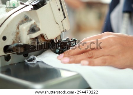 close up portrait of hands of worker and industrial sewing machine