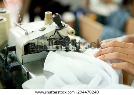 portrait of industrial sewing machine and item of clothing at textile factory