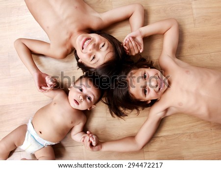 adorable three handsome brothers smiling and holding hands together while lying on the floor