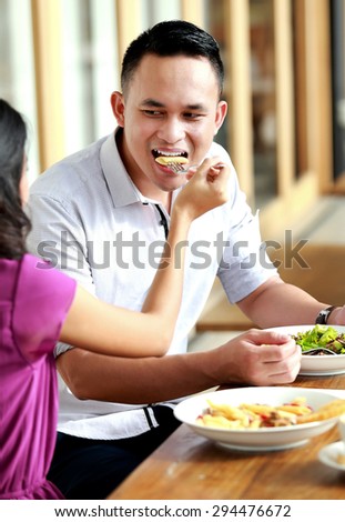 portrait of handsome man fed by his girlfriend when have a lunch