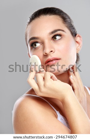 portrait of beautiful young model applying some powder using powder puff