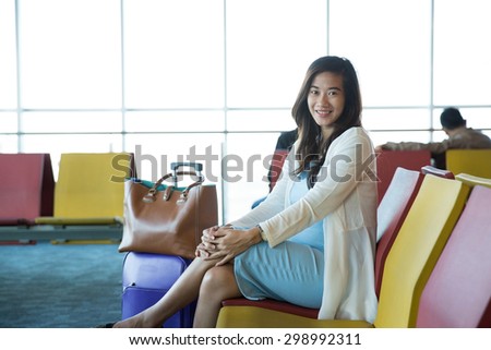 Woman in the airport lounge sitting in chair by the window waiting for her schedule to fly