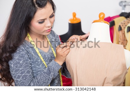 A portrait of a fashion designer or Tailor working on a design or draft, fix it with sewing needle