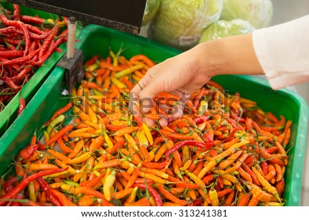 A portrait of Chili pepper on the stall in the market, asian herbs. hand trying to grab some