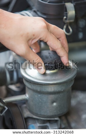 A portrait of a hand checking for power steering oil, machine related