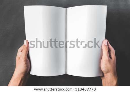close up portrait of hands holding an open book with blank page on dark background