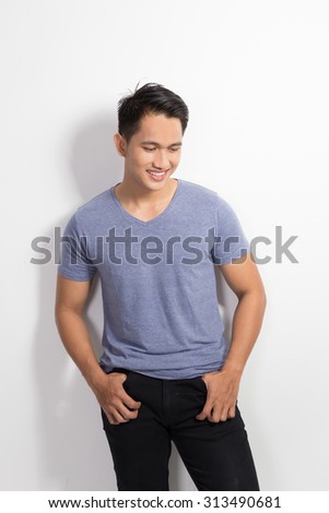 A portrait of happy young asian man leaning on wall posing hands on the waist, smile to the camera