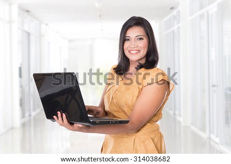 A portrait of middle aged Asian woman holding an open laptop
