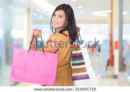 A portrait of happy middle aged Asian woman holding shopping bags