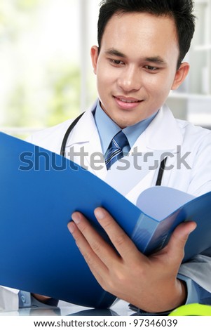 portrait of medical doctor reading a report document at his office