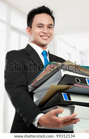 smiling business man holding stack of files and folders