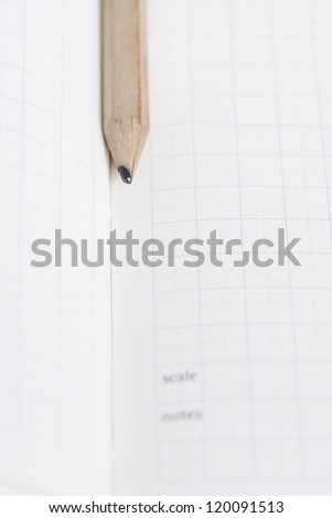 Pencil resting on blank squared note paper.