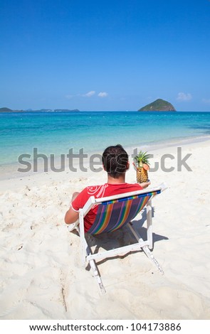 Man with cocktail on the chair near the sea