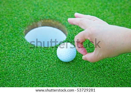 Player putting golf ball in the hole