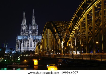 COLOGNE, GERMANY - Jan. 18, 2014: Cologne Cathedral (Koelner Dom) and railway bridge over the Rhine river at night.