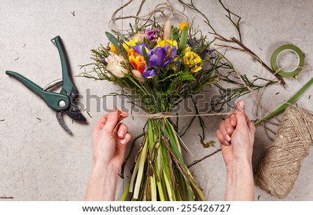 hands of florist making bouquet spring flowers