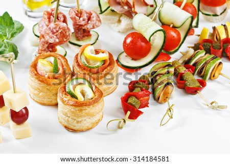 close-up view set of canapes with vegetables, salami, seafood, meat and decoration on whie plate studio isolated