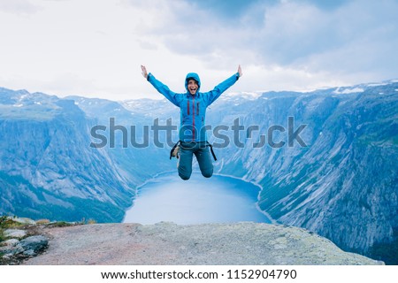 Young excited sporty woman hiker in blue jacket jumping on Norway mountain plateau. Scenic fjord on background, Norway. Foto stock © 