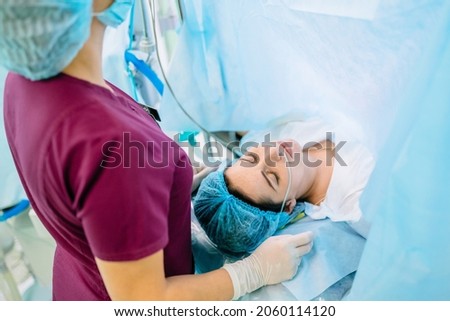 Female octors anesthetist are using tools to anesthesiologist procedures on female patient in the anesthetic machine inside operating room. Cesarean with epidural anesthesia. Stock foto © 
