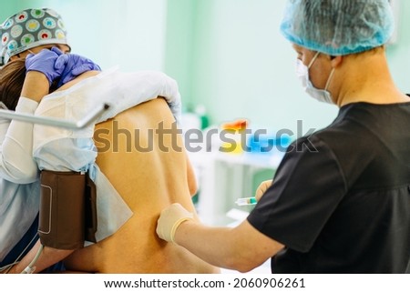 Male doctor injecting Epidural Anesthesia for pregnancy Labor during childbirth for woman pathient in hospital. Spinal anesthesia. Doctor makes a puncture in the lumbar spine Stock foto © 