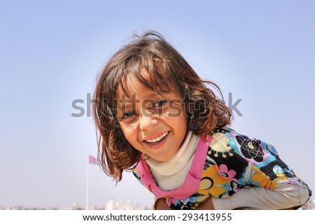 AMMAN, JORDAN - APRIL 07: unidentified happy Jordan little girl asking for being photographed and smiling to the camera on the citadel top of Amman city, Jordan on April, 17, 2014