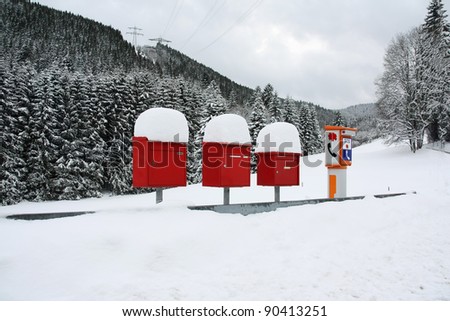 Letter boxes are covered with snow beside an SOS phone device in a remote mountain village